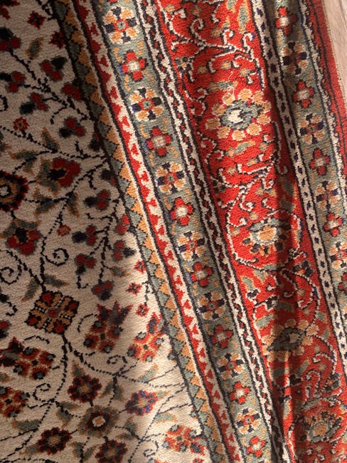 Close-up view of a traditional Persian-style rug with intricate floral patterns and borders in shades of red, beige, blue, and cream. The rug's surface appears clean and well-maintained, with a slight sheen indicating recent or professional deep cleaning. The detailed motifs include small flowers and vine-like designs along the borders, contrasting with the more densely patterned central area. The rug is laid on a wooden floor in a well-lit room, with natural light highlighting its vibrant colors and pristine condition. This image showcases the effectiveness of surface cleaning and maintenance provided by Harrow Carpet Cleaning, as depicted in the Rug cleaning Harrow on the Hill restoration case study, HARROW.